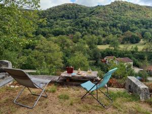 two chairs and a table with a view of a mountain at La Vie du Bief in Bolozon