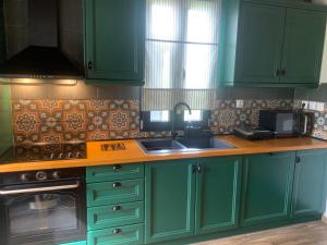 a kitchen with green cabinets and a sink at Villa Matsika in Moúdhros