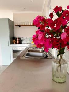 a vase of pink flowers on a counter in a kitchen at Stylish Garden Retreat in Cape Town