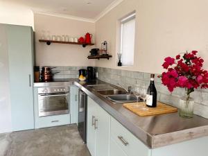 a kitchen with a sink and a counter with red flowers at Stylish Garden Retreat in Cape Town