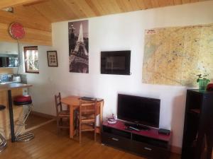 un salon avec une table, une télévision et une carte dans l'établissement Normandy cottage, à Gagny