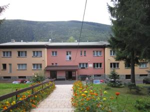 Hotel U Přehrady في Morávka: مبنى امامه ممشى وزهور