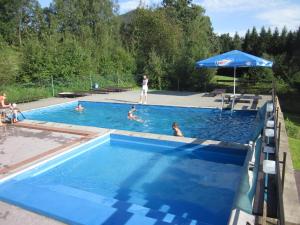 Morávka的住宿－水壩酒店，一群人在带遮阳伞的游泳池里