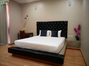 a bedroom with a large white bed with a black headboard at Sawasdee​ Buriram​ Resort in Buriram