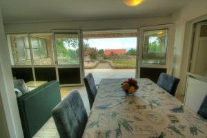 ein Esszimmer mit einem Tisch und einigen Stühlen sowie einem Tisch und einer Liege in der Unterkunft Villa Vuka in Omišalj