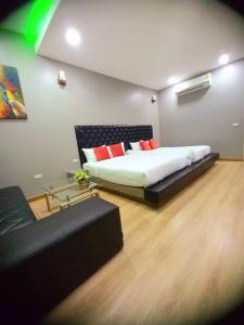 1 dormitorio con cama con almohadas rojas y sofá en Sawasdee​ Buriram​ Resort en Buriram