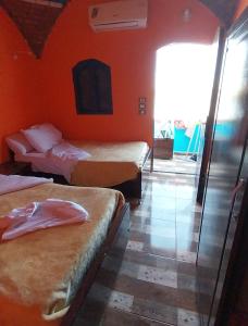 a hotel room with two beds and an orange wall at NeNeKaTo Nubian House in Aswan