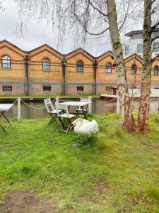 eine Ente steht neben einem Tisch und Stühlen in der Unterkunft Portobello Dock Canalside Apartment in London