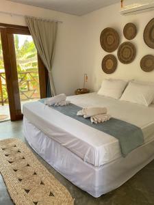 Ein Schlafzimmer mit einem großen weißen Bett und Hüten an der Wand in der Unterkunft Casa Éolica in Barra Grande