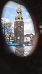 un bâtiment avec une tour d'horloge au milieu d'une rivière dans l'établissement Amsterdam Center - Houseboat B&B by Captain Ricard, à Amsterdam