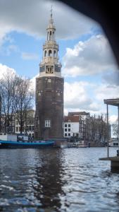 un bâtiment avec une tour d'horloge sur l'eau dans l'établissement Amsterdam Center - Houseboat B&B by Captain Ricard, à Amsterdam