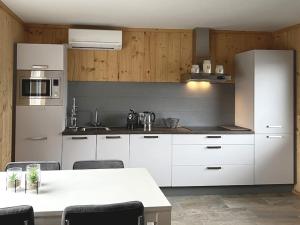 uma cozinha com armários brancos e uma mesa com cadeiras em Sunny view Egmond em Egmond-Binnen