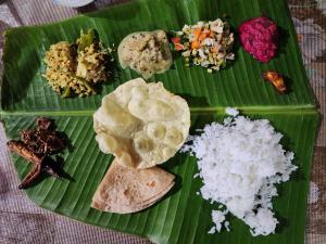 a green plate of food on a banana leaf at Spice Garden Farm house in Sultan Bathery