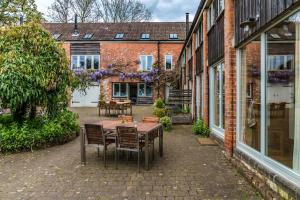 eine Terrasse mit einem Holztisch und Stühlen vor einem Gebäude in der Unterkunft Ottery St Mary Cottages in Ottery Saint Mary