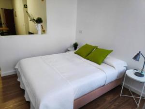 uma cama branca com almofadas verdes num quarto em Pérola da Terra - Estúdio no centro de Setúbal em Setúbal