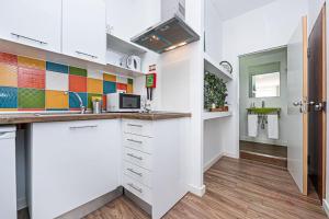 uma cozinha com armários brancos e azulejos coloridos na parede em Pérola da Terra - Estúdio no centro de Setúbal em Setúbal