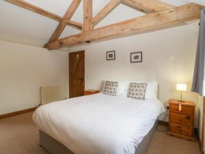 a bedroom with a white bed and a wooden ceiling at Peartree Cottage in Worcester