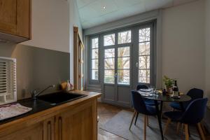uma cozinha com um lavatório e uma mesa com cadeiras em Résidence Harmonie Appartement N 1 Haut de gamme Avec Petit Déjeuner em Néris-les-Bains