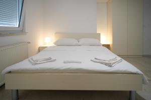 un letto bianco con lenzuola bianche e 2 pantofole di Apartments Choice a Velika Gorica