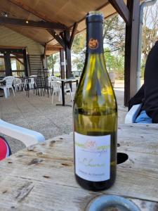 una botella de vino sentada en una mesa de madera en Camping La Maltournée en Sigloy