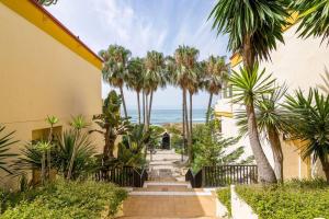 un corridoio del resort con palme e l'oceano di OleHolidays 726 Romana Playa junto al mar a Marbella