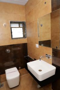 a bathroom with a sink and a toilet and a window at Hotel Annapura Residency, Chalisgaon in Chālisgaon