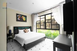 um quarto com uma cama e uma grande janela em Hoi An Town Home Resort em Hoi An