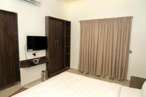 1 dormitorio con 1 cama, TV y ventana en Hotel Annapura Residency, Chalisgaon, en Chālisgaon