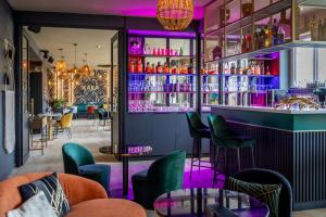 サンタンヌ・ドーレーにあるBrit Hotel Kara Sainte Anne d'Aurayの紫色の照明と緑の椅子が備わるバー