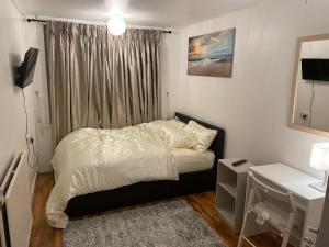 a small bedroom with a bed and a desk at Two bedroom flat in London near the 02 in London