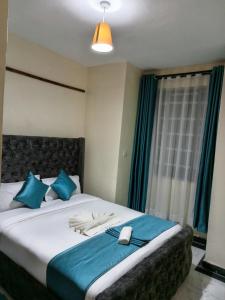 a bedroom with a large bed with blue pillows at SAFNEST Furnished Apartment in Nakuru