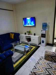 a living room with a blue couch and a tv at SAFNEST Furnished Apartment in Nakuru