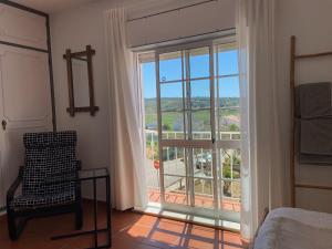 um quarto com uma janela com uma cadeira e uma vista em Guesthouse Releash Aljezur em Aljezur