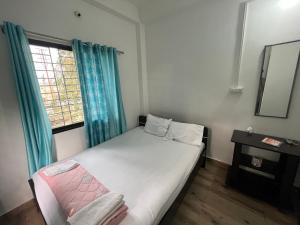 a small bedroom with a bed and a window at Marigold Hotel in Siliguri