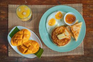 a plate of breakfast food with eggs and bread and orange juice at Inigtan Lio Bamboo Cottages in El Nido