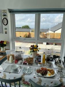 uma mesa com comida para o pequeno almoço em frente a uma janela em Number 14 em Downpatrick