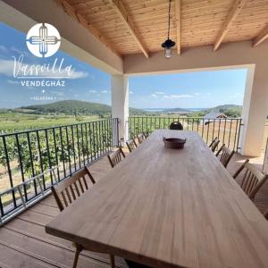 una mesa de madera y sillas en una terraza con vistas en Vass Villa Vendégház Felsőörs, en Felsőörs