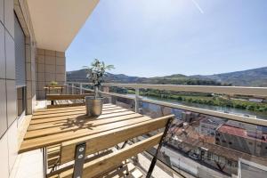 d'un balcon avec une table en bois et une vue sur la rivière. dans l'établissement Casa da Tia Douro, à Peso da Régua