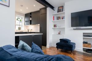 a living room with a blue couch and a kitchen at Central London apartment in Vauxhall near big Ben in London