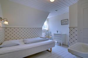 亨能史特蘭德的住宿－Det Gamle Badehotel - Klitgaarden，一间卧室配有一张床和一个水槽和一个浴缸