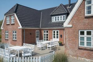 亨能史特蘭德的住宿－Det Gamle Badehotel - Klitgaarden，砖屋,设有配有白色桌椅的庭院