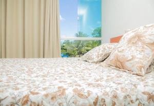 - un lit avec une couette et des oreillers blancs dans l'établissement Pousada Serra Mares, à Ilhéus