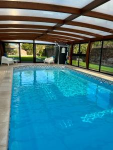 una gran piscina azul con techo de madera en Gîte avec piscine, en Lestrem