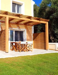 a wooden pergola with a table on a patio at Reiki Apartments in Ereikoússa
