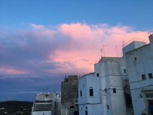 a group of white buildings under a cloudy sky at La Racioppola in Ostuni