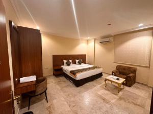 a bedroom with a bed and a chair and a table at Star Apartments in Salalah