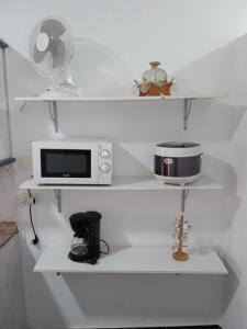 a kitchen with white shelves with a microwave and a fan at Arenas del mar in La Mareta