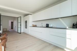 uma cozinha com armários brancos e piso em madeira em Sweet Inn - De Brouckere em Bruxelas