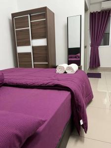 Una cama morada con dos toallas encima. en 92D’venus Residence en Sitiawan