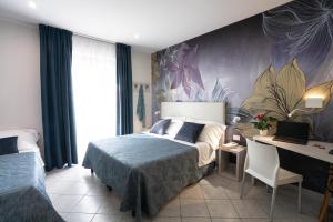 a bedroom with two beds and a desk in it at Hotel Sirio in Lido di Camaiore